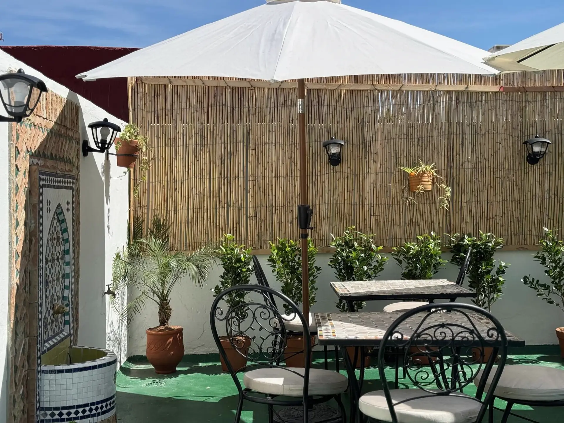 La fontaine de zellige de la terrasse au soleil, derrière les tables