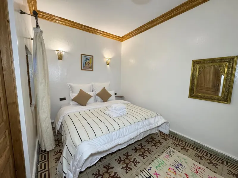 La chambre double climatisée, son lit et sa corniche dorée