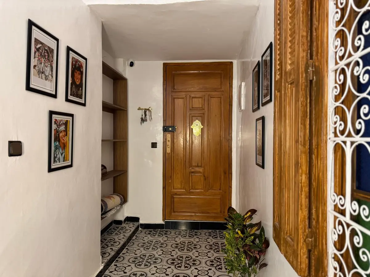 Une porte en bois au bout du couloir, près d'une grille blanche