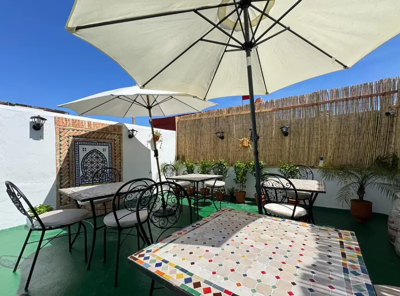 Une table en mosaïque sous les parasols de la terrasse