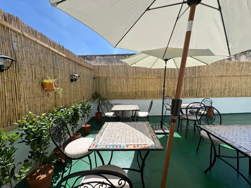 Une table en mosaïque sous un parasol, sur la terrasse